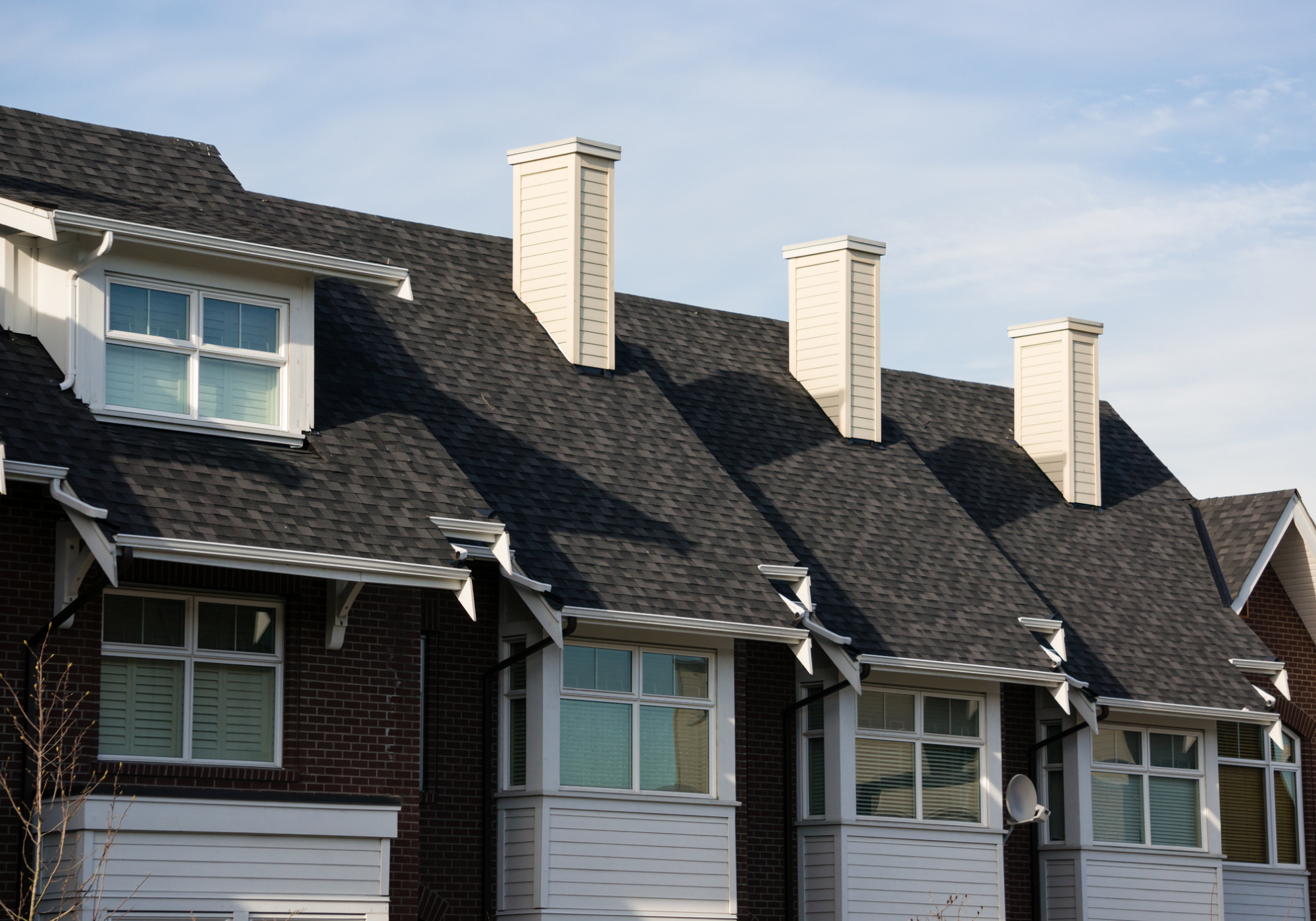 Row of modern townhouses with chimneys.
