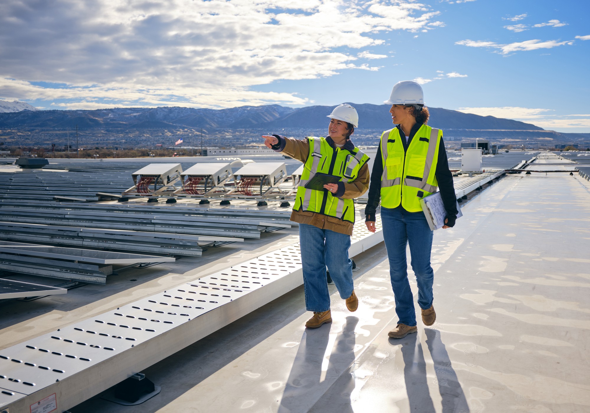 Construction workers on rooftop inspecting solar panels.