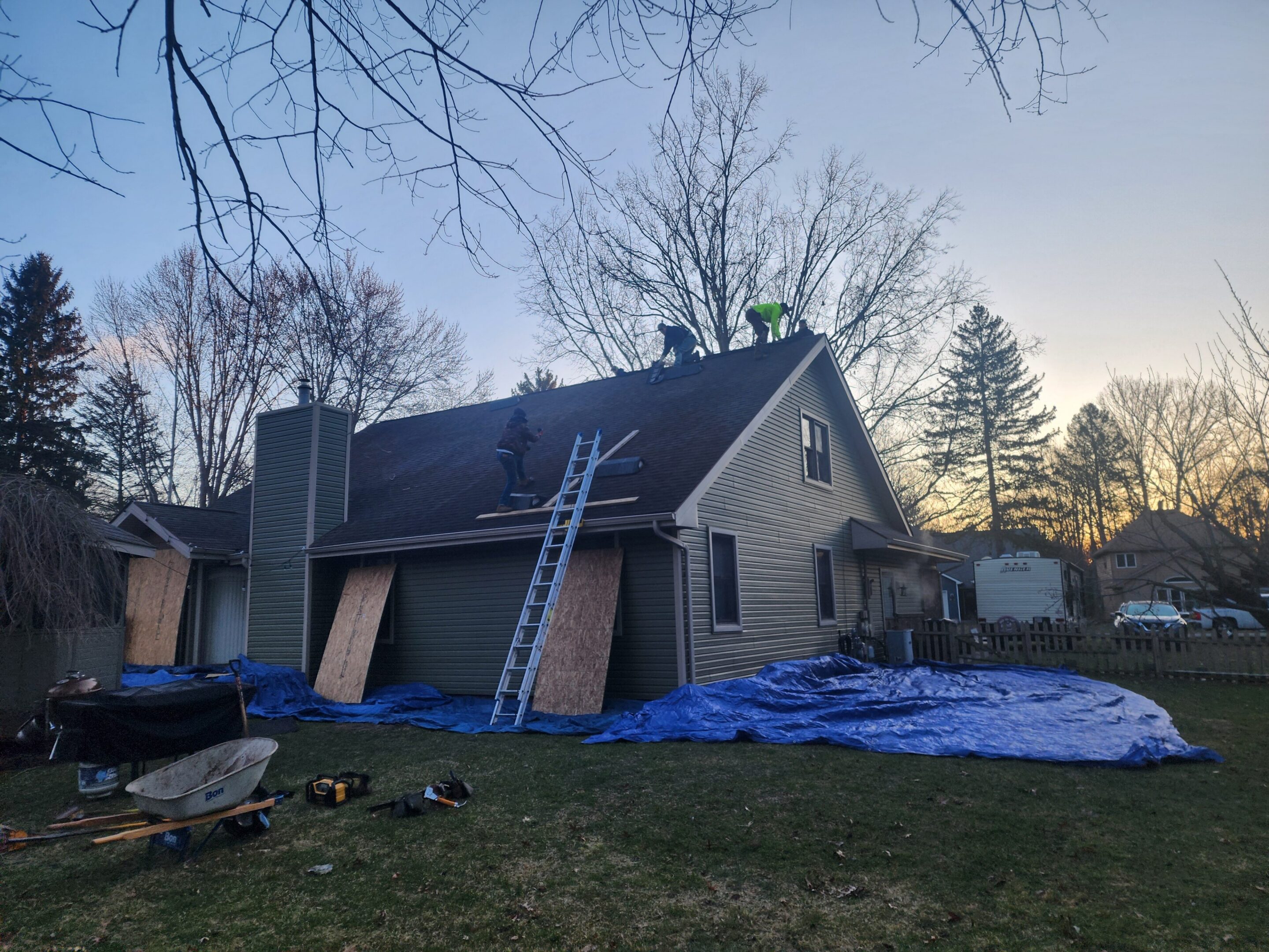 House roof repair with workers and ladders.