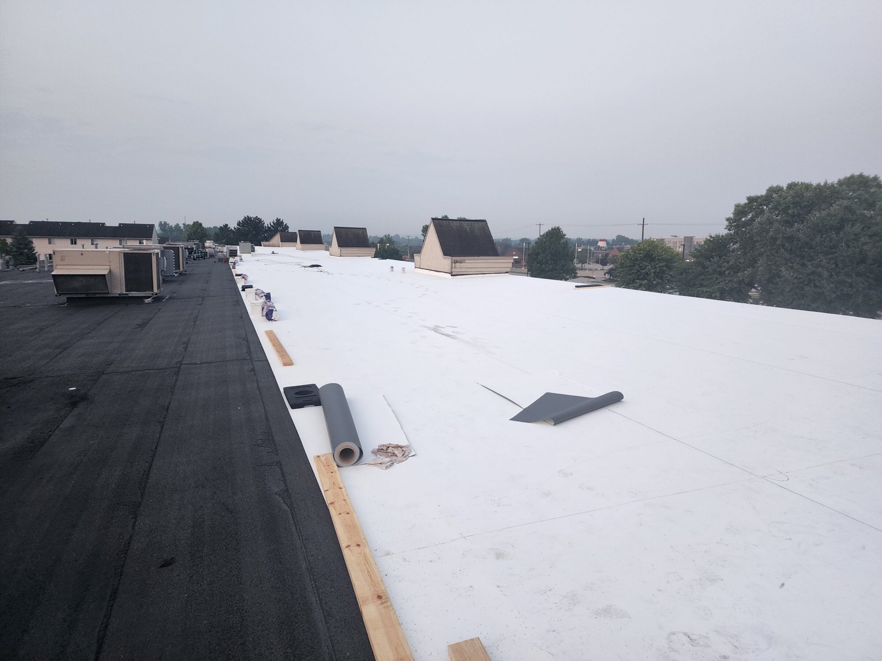 White flat roof under construction, overcast sky.