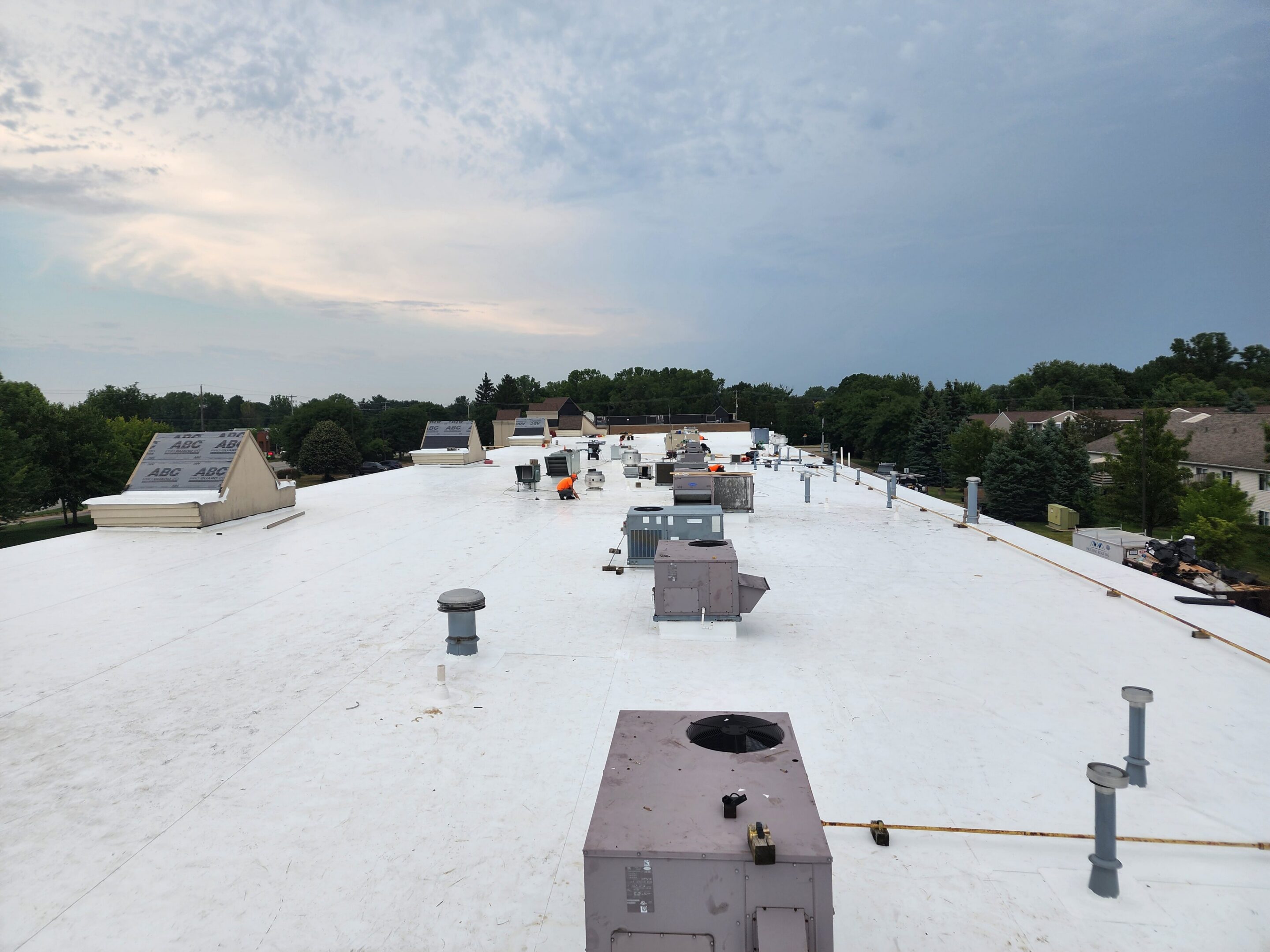White rooftop with ventilation systems, cloudy sky.