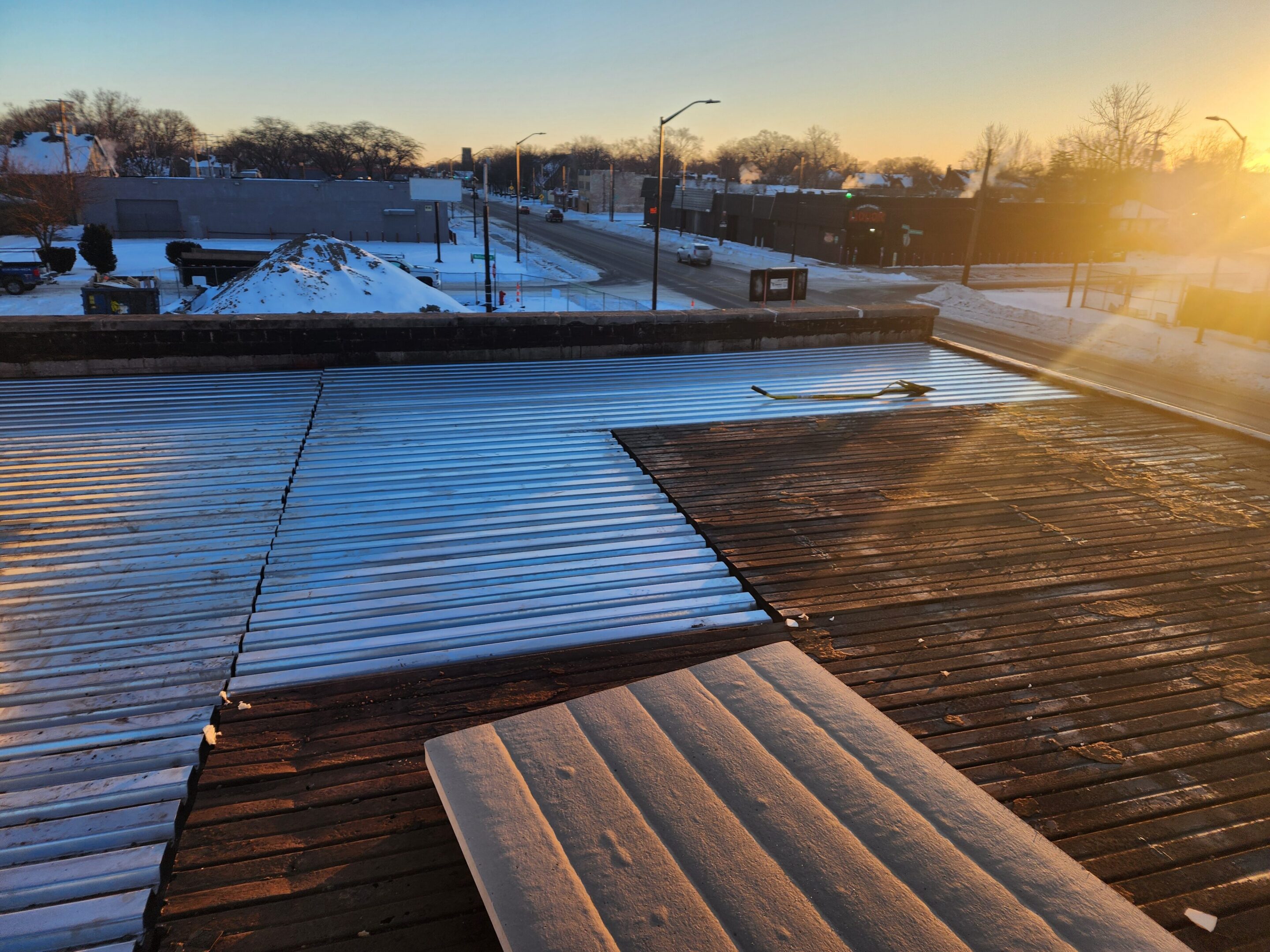 Snowy rooftop at sunrise with street view.