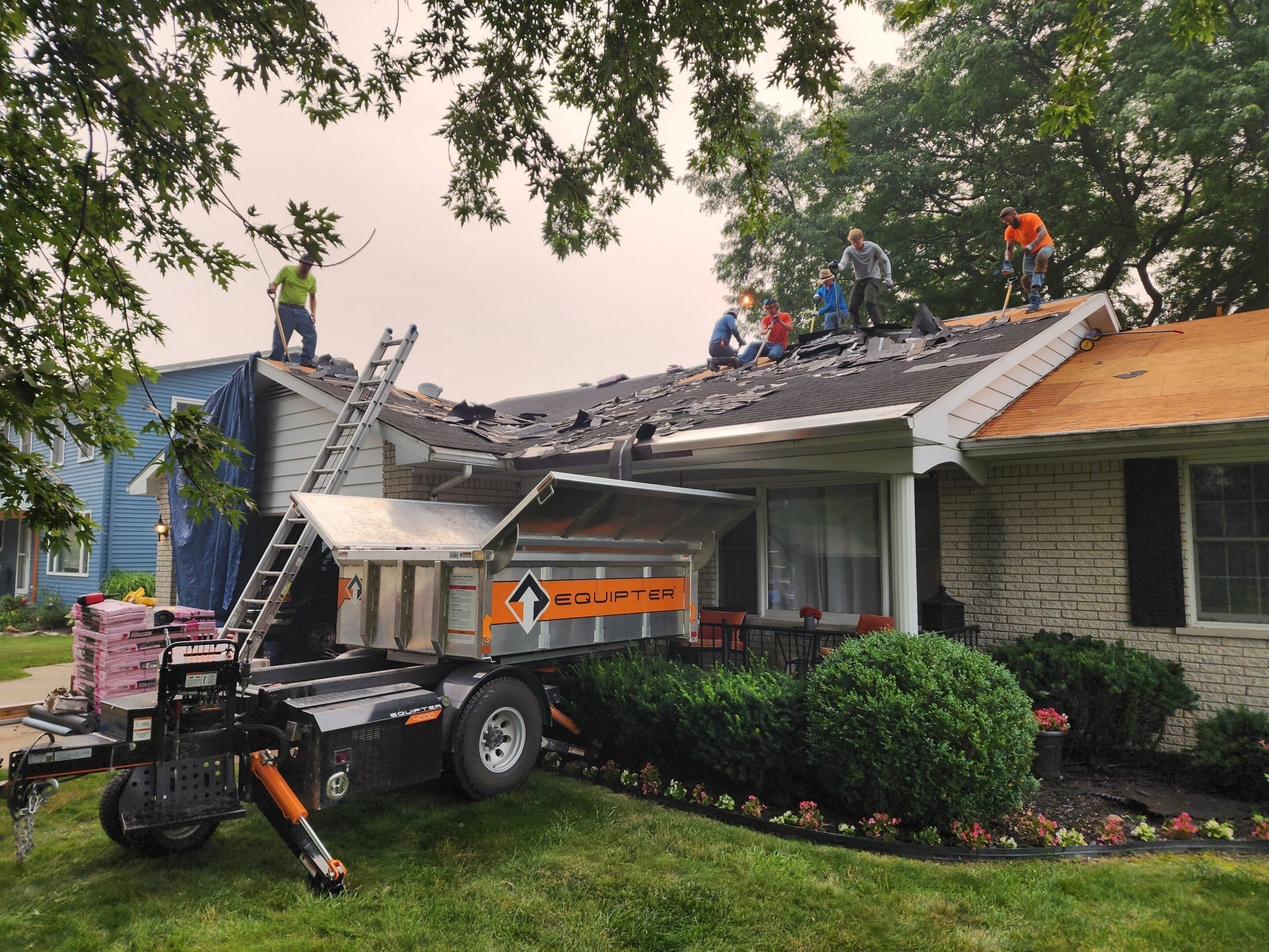 Workers repairing roof of residential house.