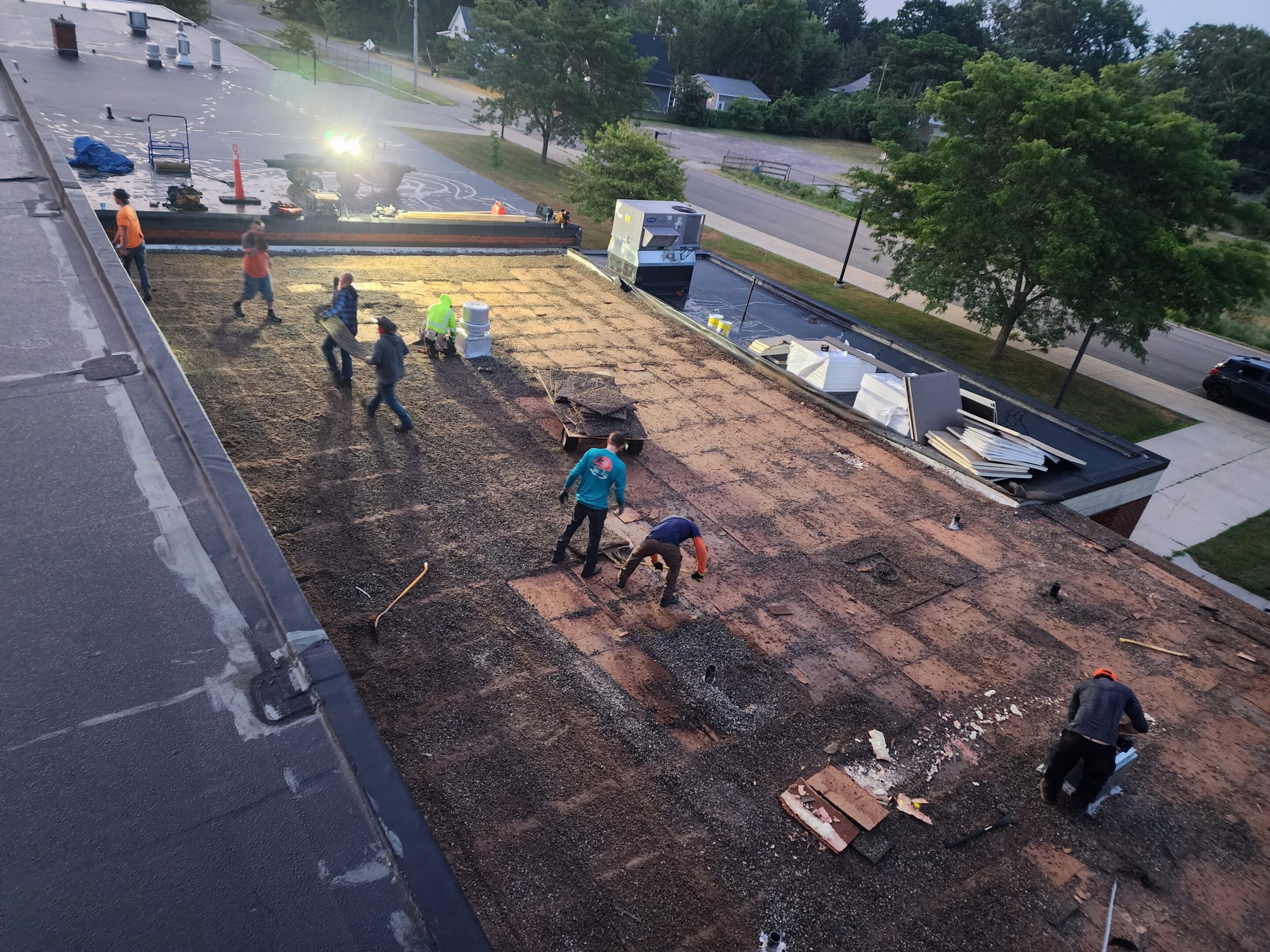 Workers repairing a flat roof at dusk.