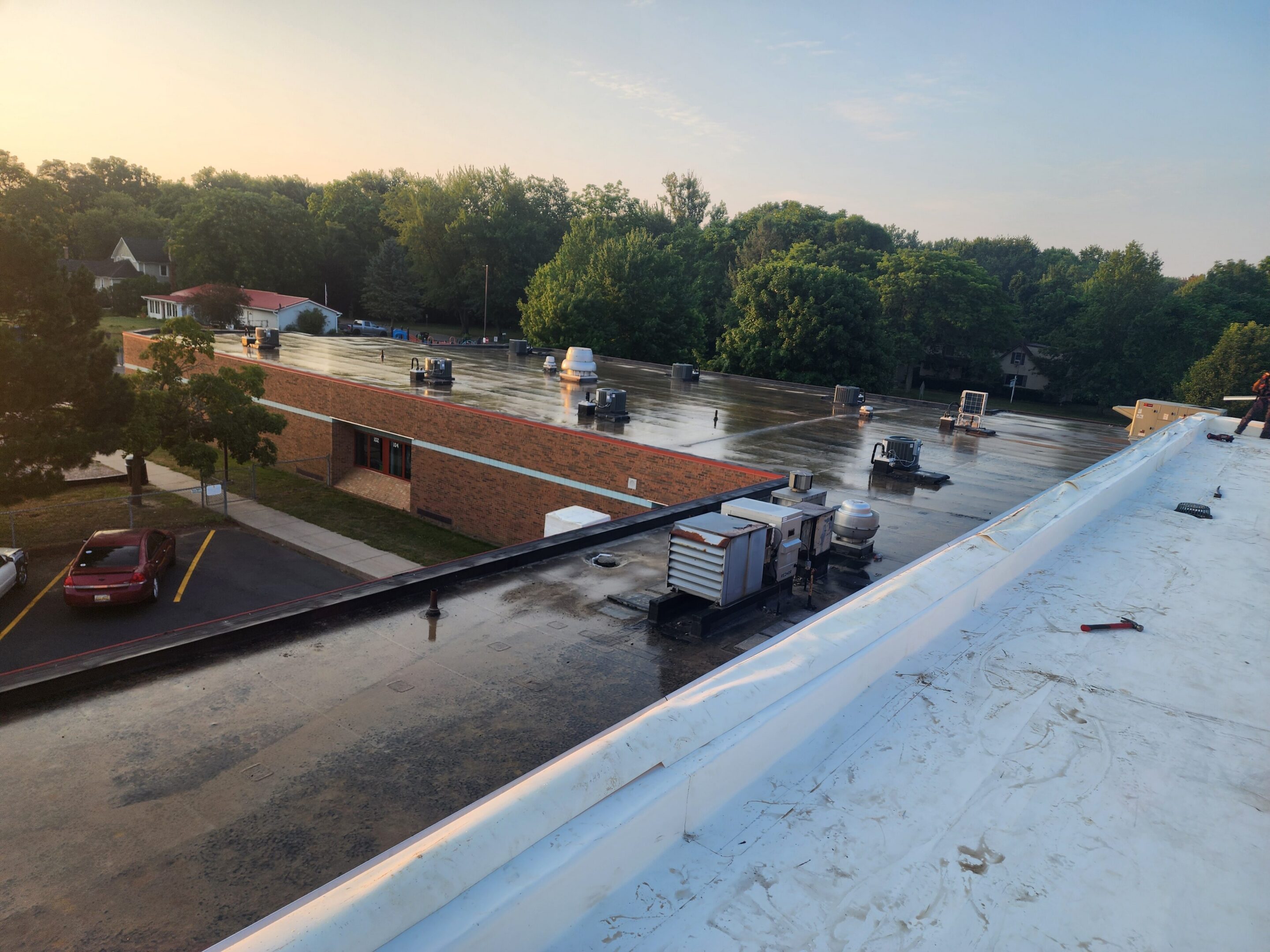 Flat rooftop with HVAC units and trees.