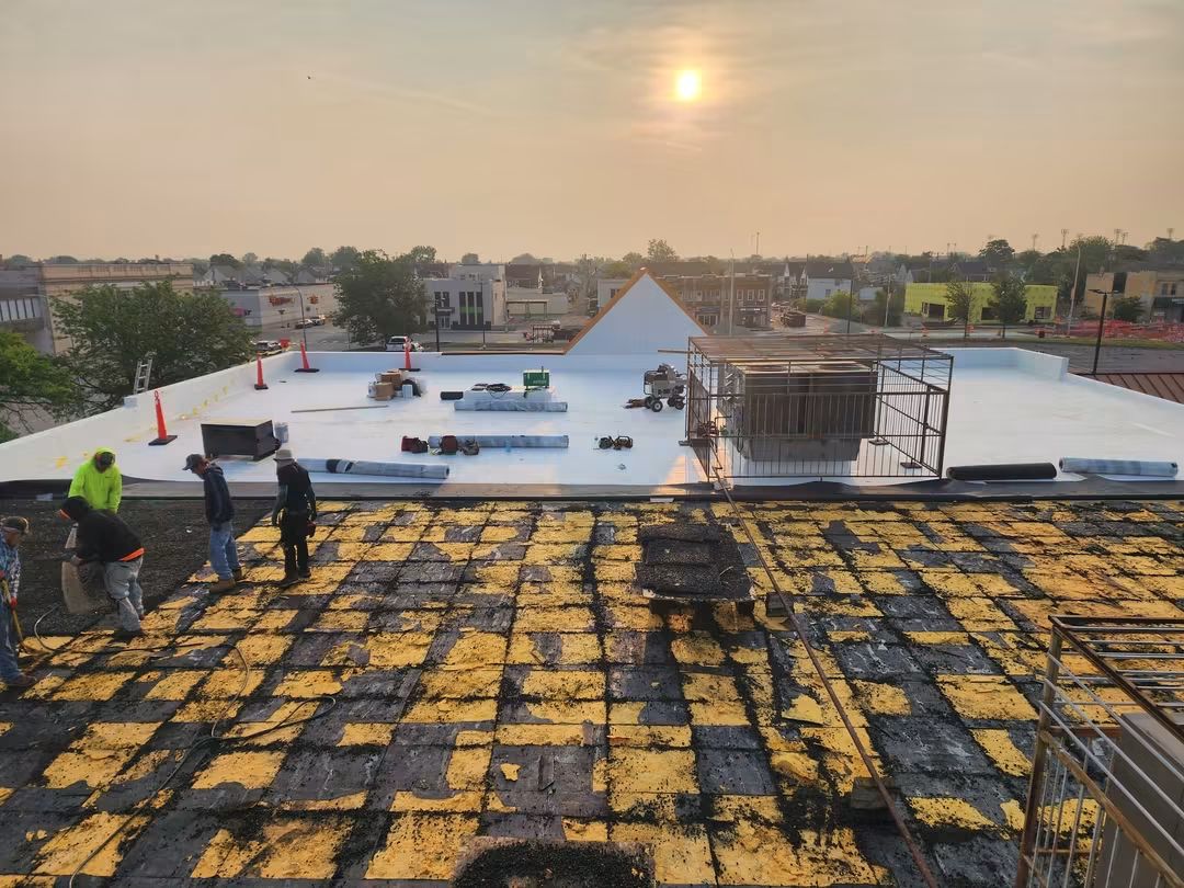 Workers on rooftop during sunset.