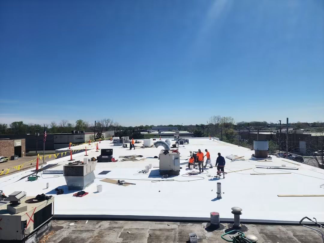 Workers on a large white rooftop project.