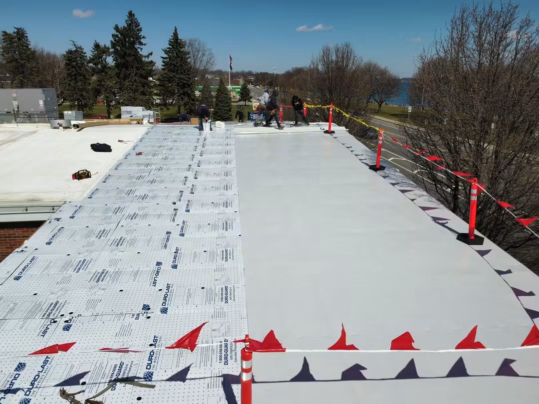 Rooftop construction with safety barriers and trees.
